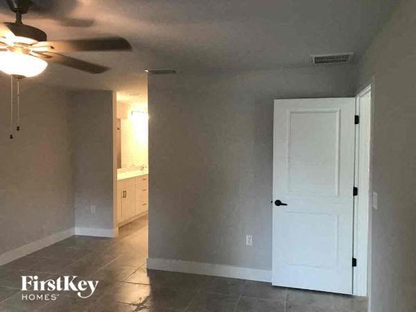 an empty living room with a ceiling fan and a white door