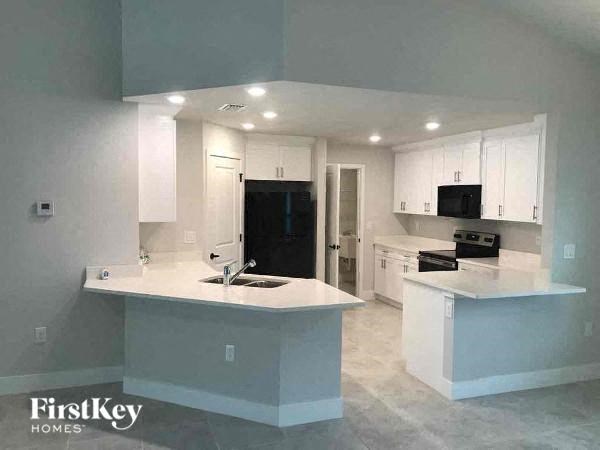 an empty kitchen with white cabinets and a sink