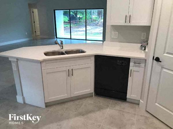 a white kitchen with a sink and a window
