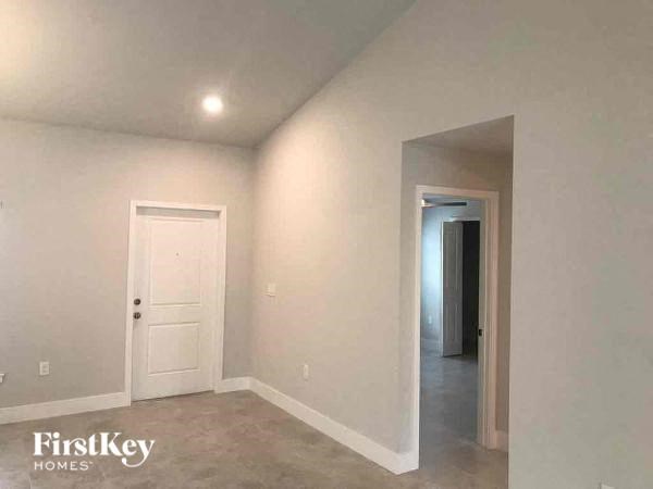 an empty living room with a white door and a hallway