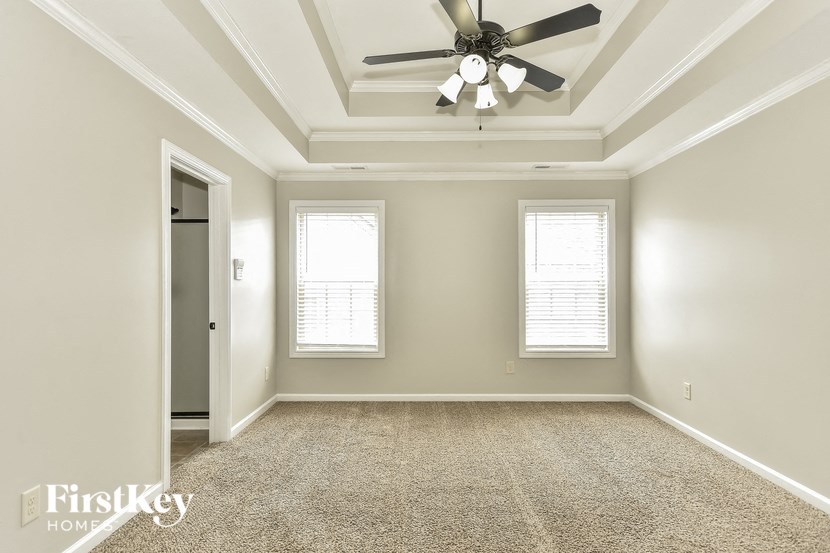 an empty room with a ceiling fan and two windows