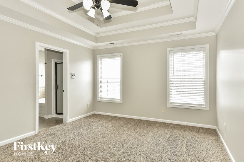 an empty living room with a ceiling fan and two windows