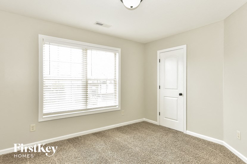 an empty bedroom with a window and a white door