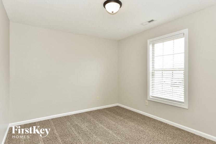 an empty room with a window and a carpet
