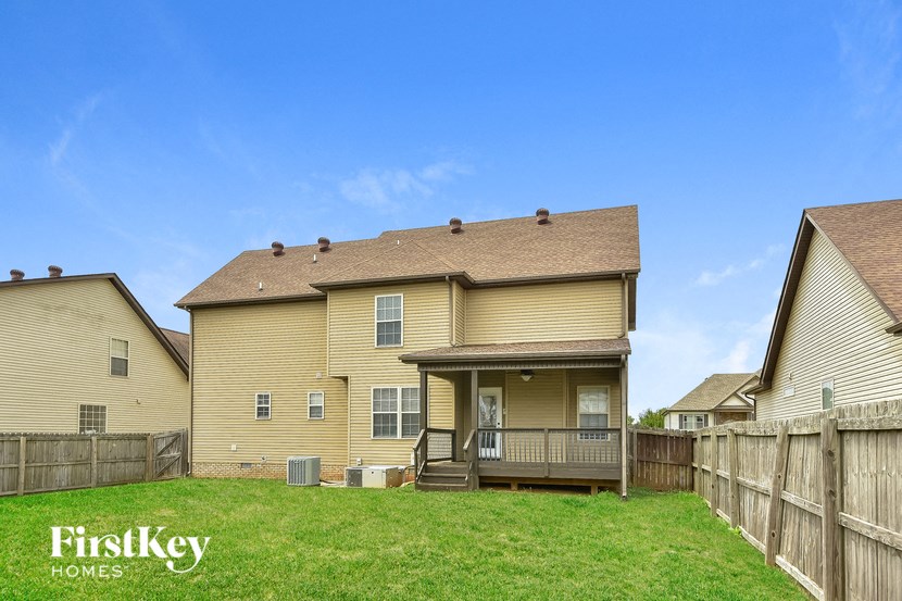the back of a house with a yard and a wooden fence