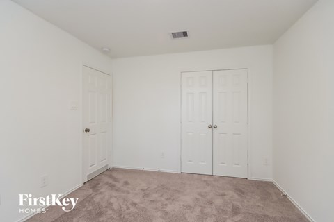 A bedroom with a carpeted floor and two white doors.