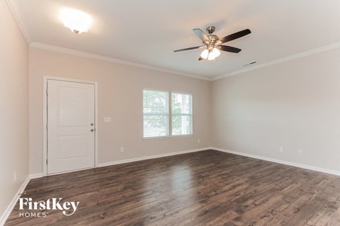 the spacious living room with wood floors and a ceiling fan