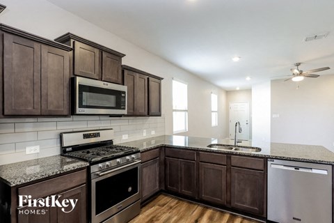 A kitchen with dark wood cabinets and a granite countertop.