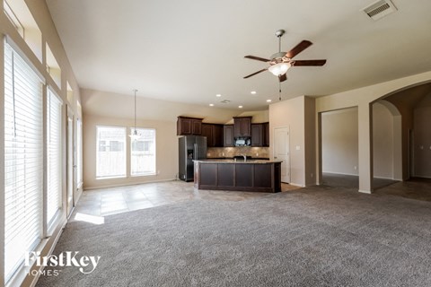 A spacious living room with a ceiling fan and a bar area.