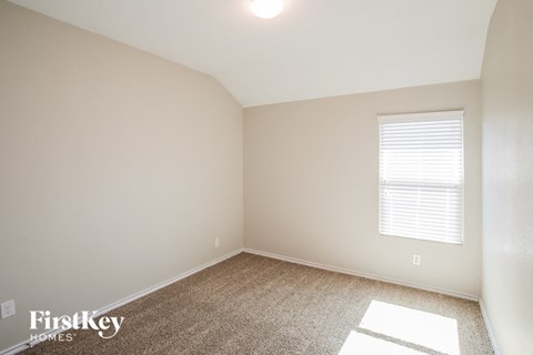 a bedroom with white walls and carpet and a window