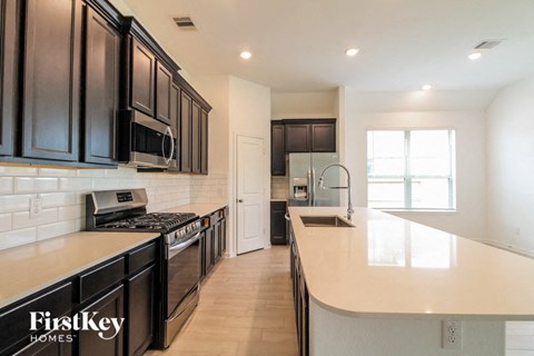 A kitchen with black cabinets and a stove top oven.