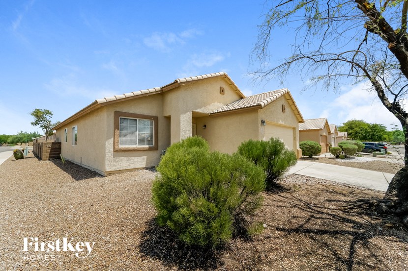a beige house with a driveway and some bushes