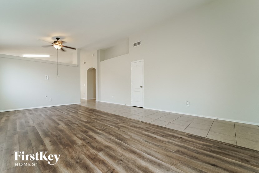 the living room of an empty house with a ceiling fan