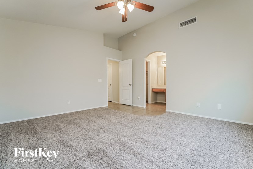 a spacious living room with carpet and a ceiling fan