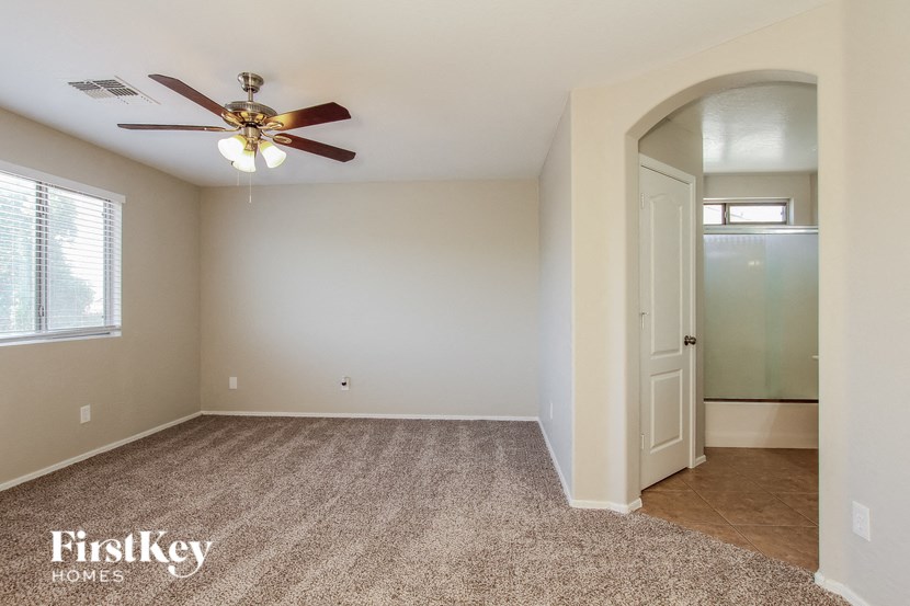 A room with a fan and a carpeted floor.