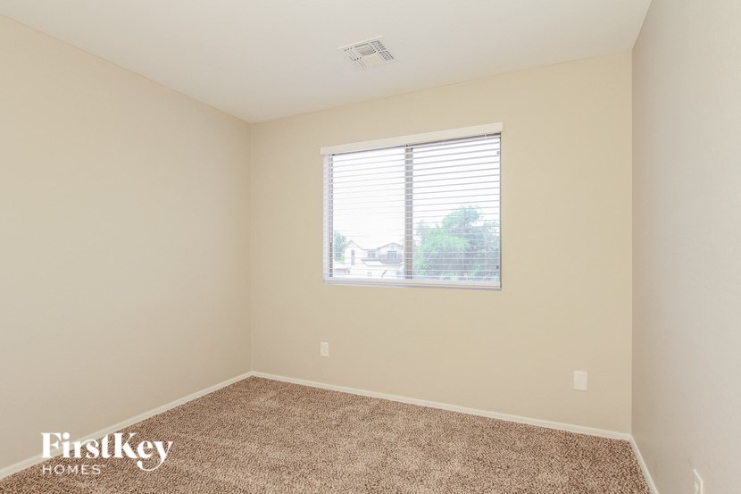 A room with a carpeted floor and a window with blinds.