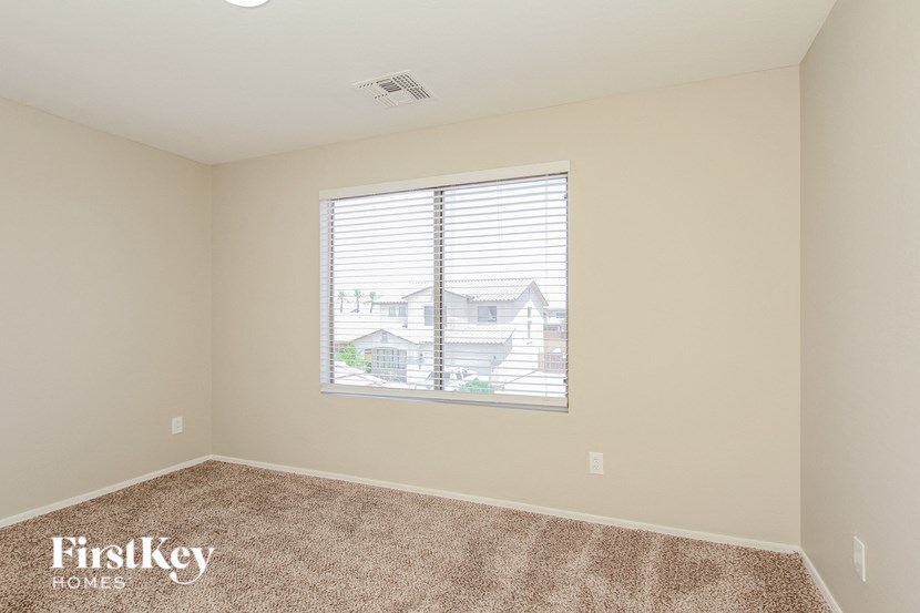 A room with a carpeted floor and a window showing a view of a house.