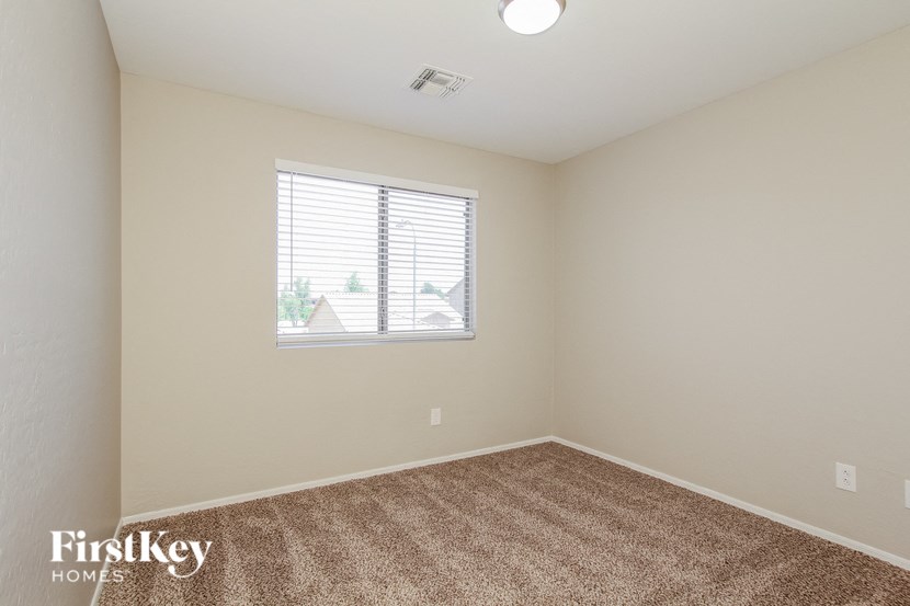 A room with a carpeted floor and a window with blinds.