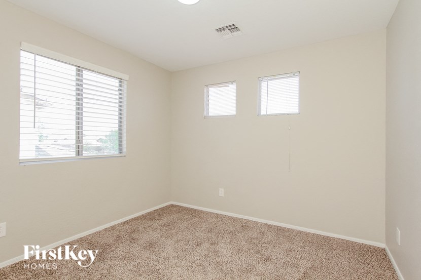 A room with a carpet floor and two windows.