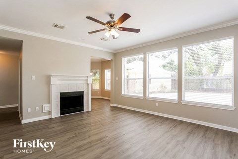 A spacious living room with a fireplace and a ceiling fan.