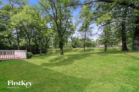 a large yard with trees and a wooden deck