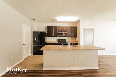 A kitchen with a white counter top and a black fridge.