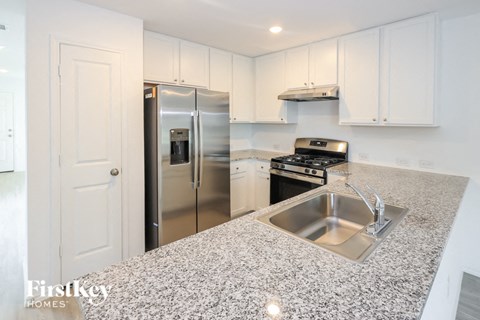 a kitchen with granite counter tops and a stainless steel refrigerator