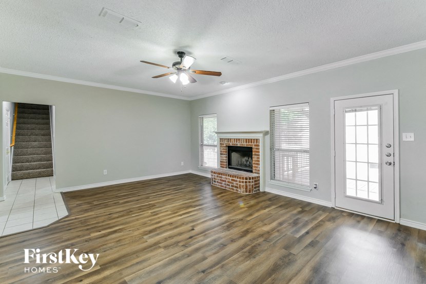 an empty living room with a fireplace and a ceiling fan