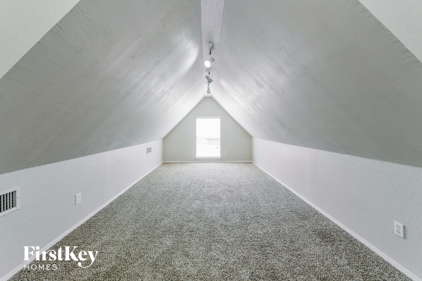 the attic of a home with a window and a carpeted floor