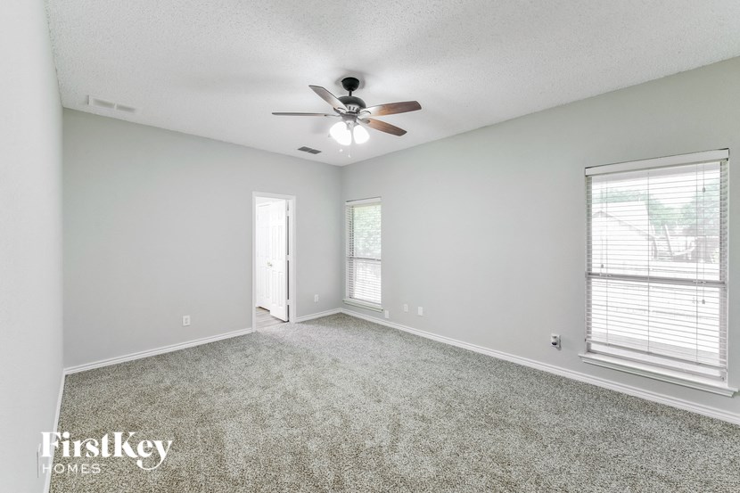 an empty living room with a ceiling fan and a window
