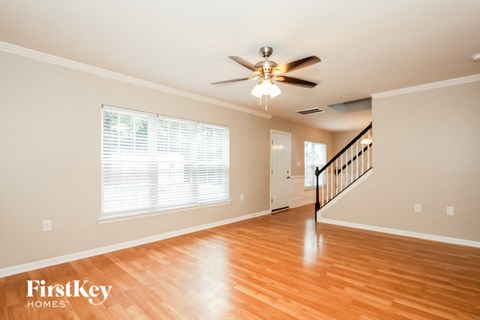 A spacious room with a wooden floor and a staircase.