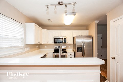 A kitchen with a white counter top and stainless steel appliances.