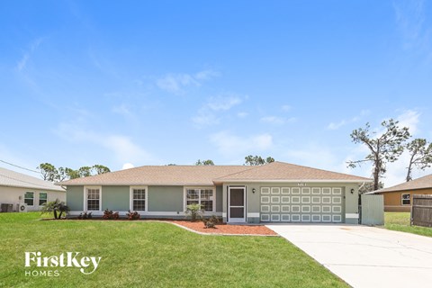 a beige house with a lawn and a driveway