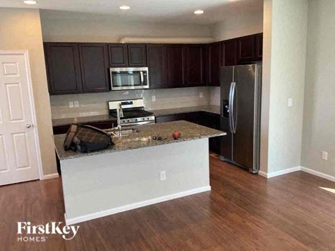 A kitchen with dark brown cabinets and a granite countertop.