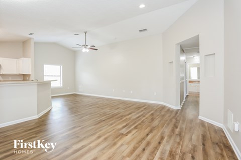 the living room and dining room with wood flooring and white walls