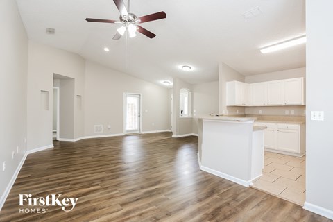 an empty living room and kitchen with a ceiling fan