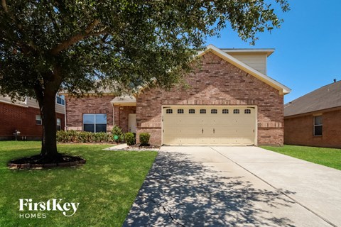 a garage door in front of a brick house with a tree
