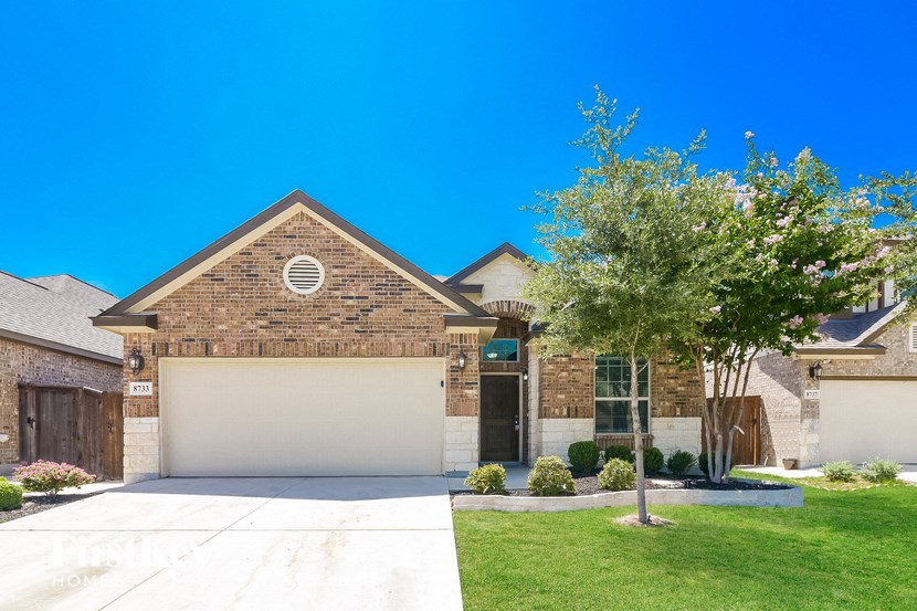 a house with a driveway and a tree in front of it