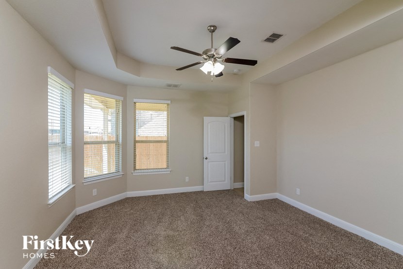 an empty living room with a ceiling fan and three windows