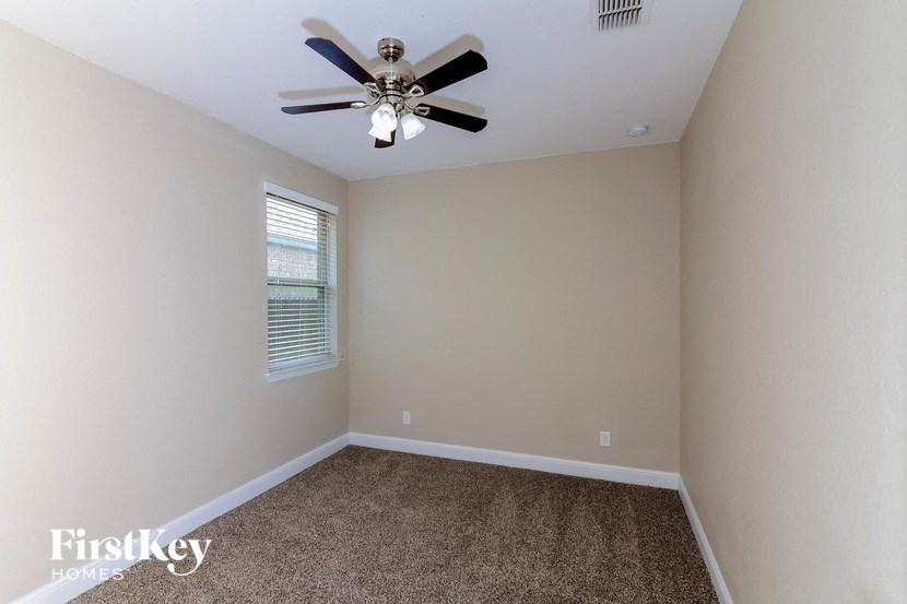 an empty room with a ceiling fan and a window