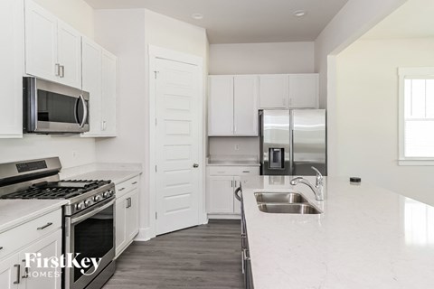 A kitchen with white cabinets and a stove top oven.