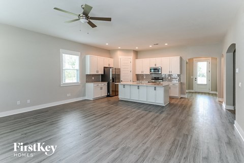 an open kitchen and living room with white cabinets and a ceiling fan