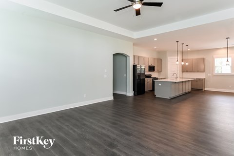 A spacious kitchen area with a ceiling fan and pendant lights.