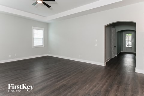 A spacious room with wooden floors and a ceiling fan.