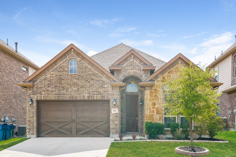 a brick house with two garage doors and a tree