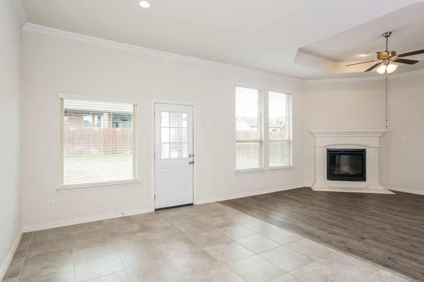 an empty living room with a fireplace and a ceiling fan
