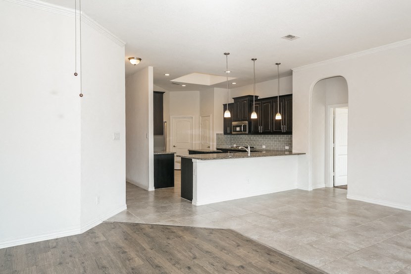 an open kitchen and living room with white walls and tile flooring