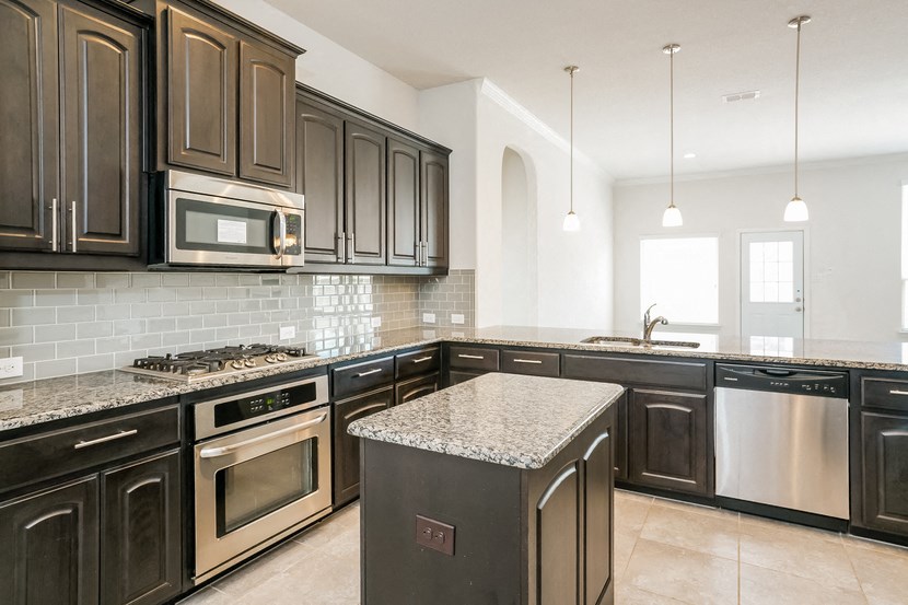a kitchen with black cabinets and granite counter tops and stainless steel appliances
