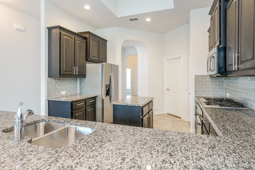 an open kitchen with granite counter tops and black cabinets