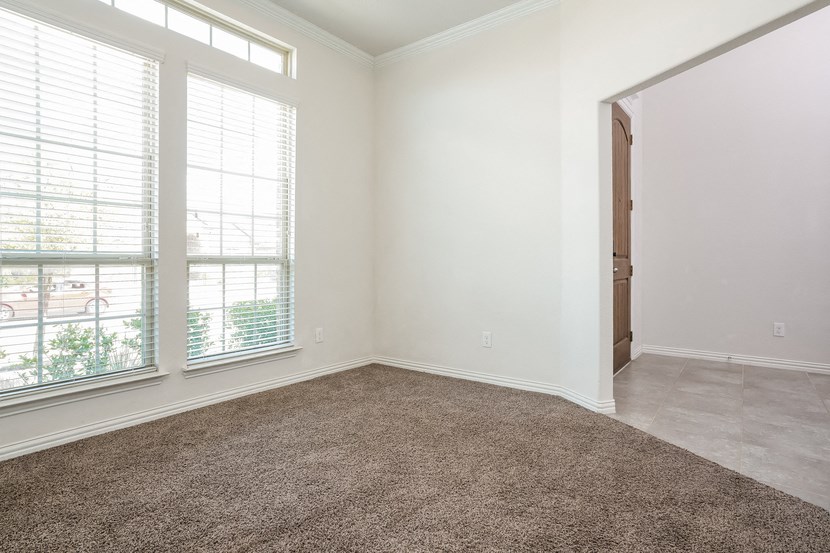 an empty room with a door and two windows